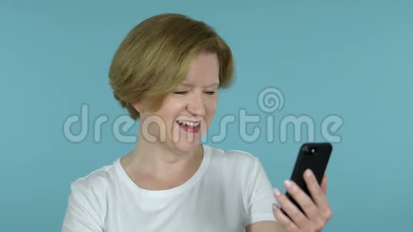 蓝底老女人通过智能手机在线视频聊天视频的预览图