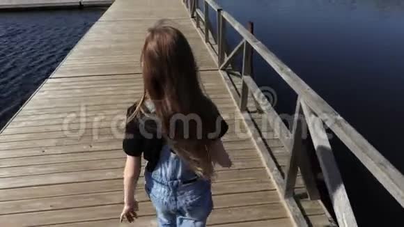 小女孩走在湖上的浮桥上视频的预览图