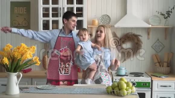 幸福的家庭在厨房妈妈抱着她的女儿爸爸妈妈唱成虚构的话筒跳舞视频的预览图