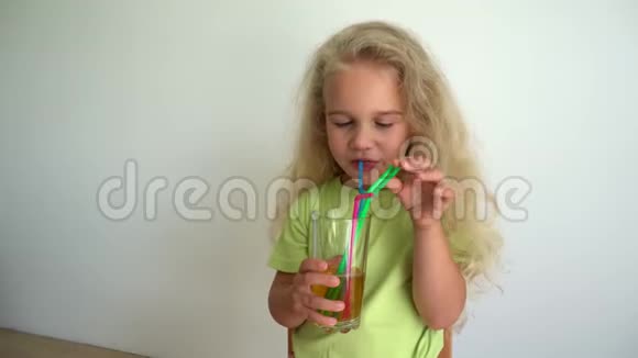 女孩公主用五颜六色的吸管从玻璃杯里喝苹果汁万向节运动视频的预览图
