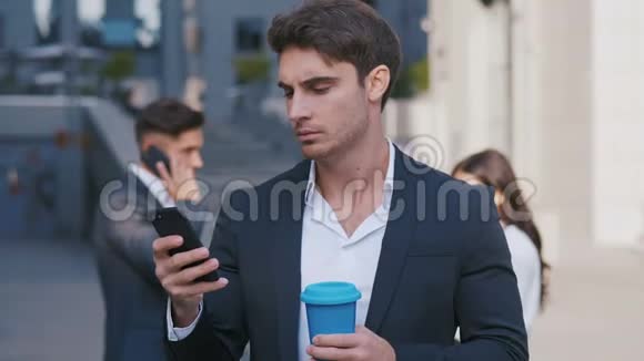 忙碌的商人使用智能手机和一群商人在后台讨论工作的肖像工作视频的预览图