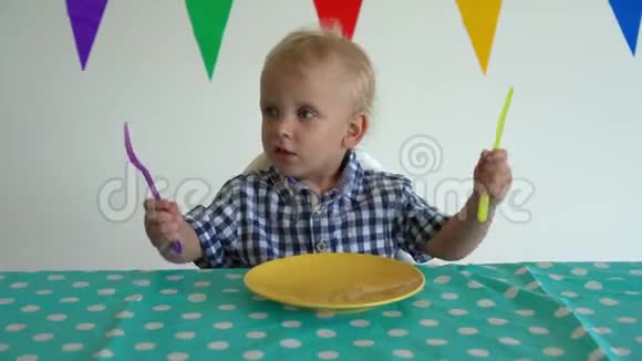 小男孩手里拿着叉子和刀打桌子万向节射击视频的预览图
