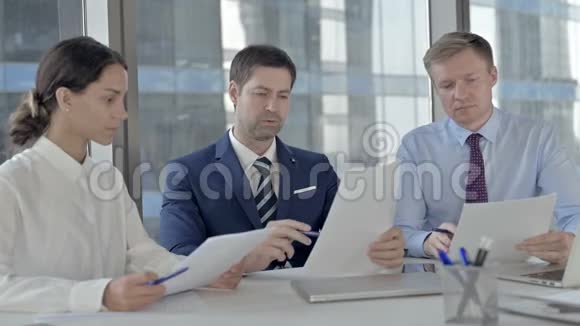 中年商人在办公室桌上为他的助手阅读文件视频的预览图