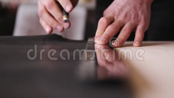 制革工人正在用剃刀和米尺剪黑色的皮视频的预览图
