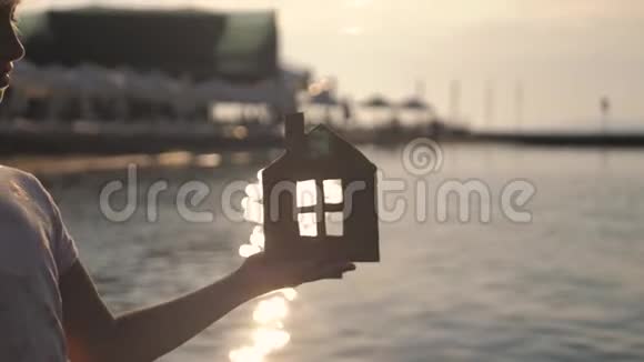 日落时女孩在海滩上拿着纸房子人梦想家庭房地产和家居理念儿童梦视频的预览图