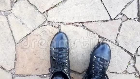 石头地板上的黑色皮靴顶部的景色视频的预览图