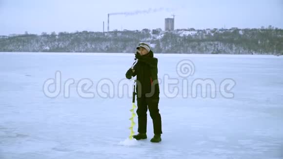 冬天一个渔夫在城里用冰钻钻洞视频的预览图