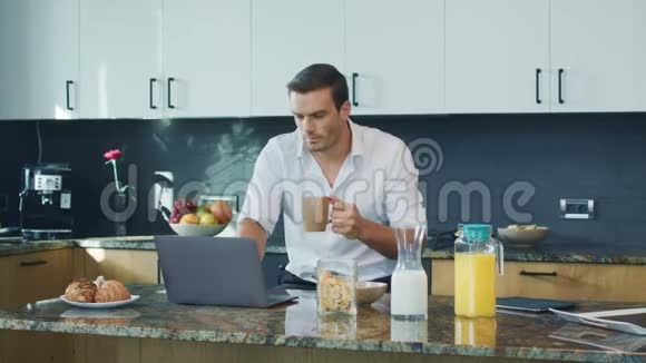 商人看视频大厨房震惊的男人看着笔记本电脑视频的预览图