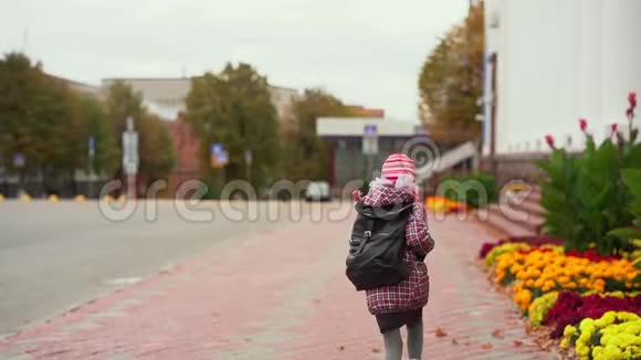 穿着红色夹克和帽子背着背包的女孩子跑去上学视频的预览图