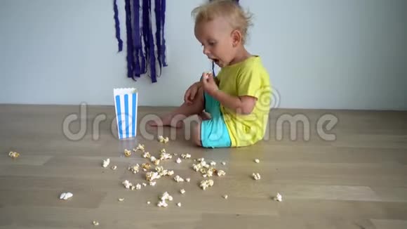 快乐的孩子坐在木地板上吃爆米花万向节运动视频的预览图
