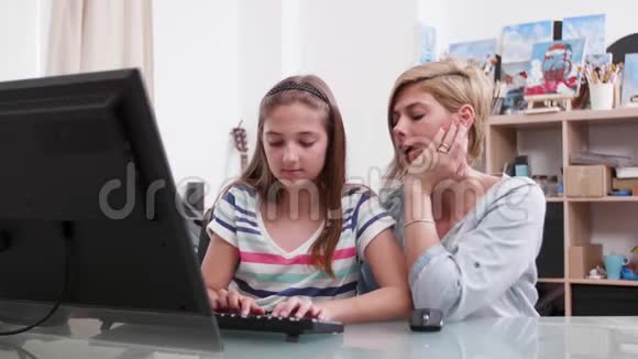 年轻漂亮的女人在电脑上帮一个十几岁的女孩发短信视频的预览图