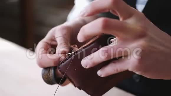这位制革工人正在缝制一个手工制作的皮夹视频的预览图