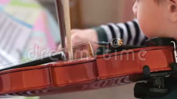 八岁的男孩正在学习拉小提琴用音符播放音乐视频的预览图