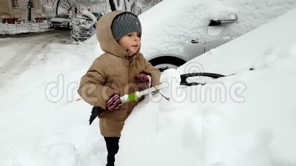 4k视频3岁幼儿男孩帮助清洁车覆盖雪后暴风雪视频的预览图