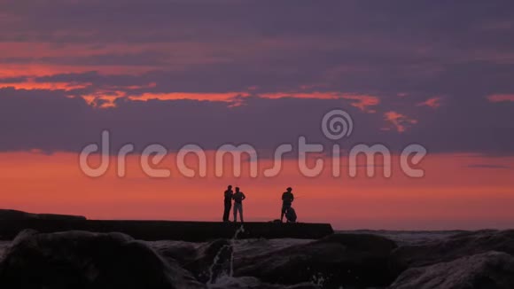 渔夫们正在美丽的日落的背景上钓鱼渔人夏日日落垂钓剪影视频的预览图