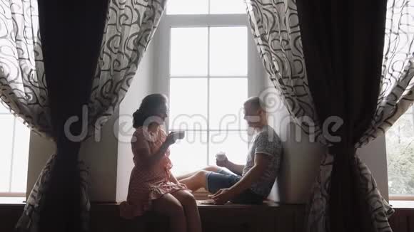 恋爱中的年轻夫妇在窗边喝咖啡视频的预览图
