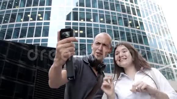 在摩天大楼的背景下游客在市中心的动作摄像机上自拍视频的预览图