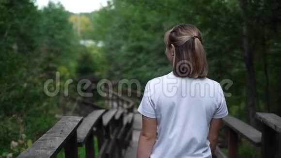 慢动作快乐的年轻女人在树林里看视频的预览图