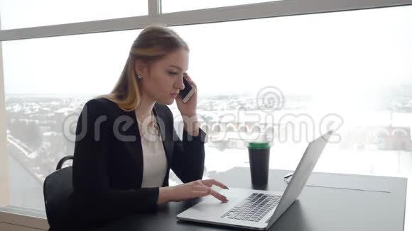 冬天有笔记本电脑的女孩在咖啡桌上通过电话说话视频的预览图