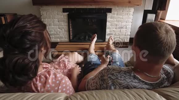 恋爱中的年轻夫妇正躺在沙发上看电视视频的预览图