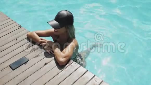 戴黑帽子的漂亮女人在游泳池里放松视频的预览图