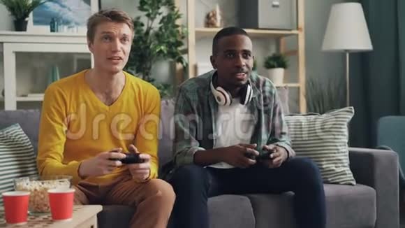 快乐的年轻人正在玩电子游戏与控制台使用操纵杆在家两个人在讨论按钮和谈话一个视频的预览图
