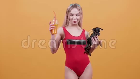 性感的金发女孩穿着一件红色泳衣一只手拿鸡尾酒另一只手拿狗视频的预览图