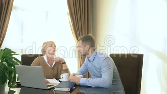 男人和女人坐在办公室手提电脑前说话视频的预览图
