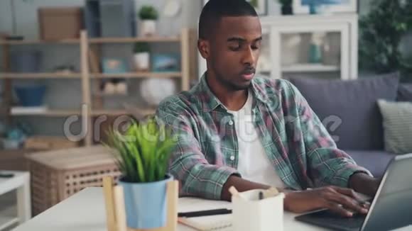 疲惫压力大困倦的自由职业者非裔美国人正在使用笔记本电脑在家工作打哈欠的感觉视频的预览图