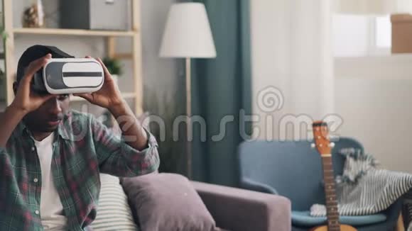 非裔美国学生在家里玩虚拟现实眼镜戴上设备和移动手臂放松视频的预览图