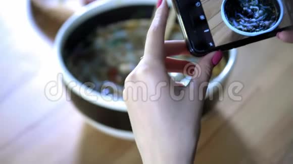 一个女孩在智能手机上制作一张食物照片与朋友分享一张社交网络中的食物照片亚洲咖啡厅视频的预览图