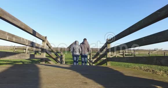 男女手牵着手走过小木桥背景是青蓝的天空生活方式视频的预览图