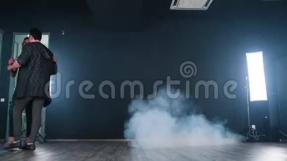 一对漂亮的情侣在舞蹈室的黑色背景前跳舞视频的预览图