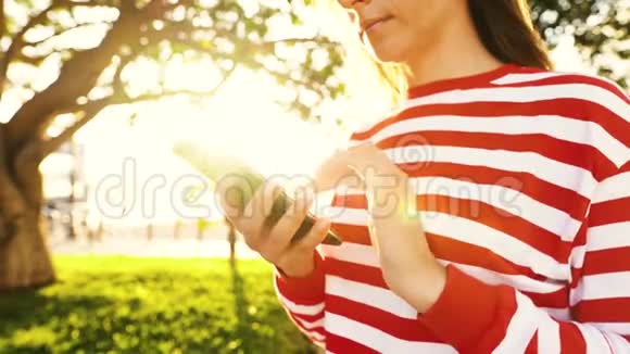在户外对着夕阳使用智能手机的女人视频的预览图