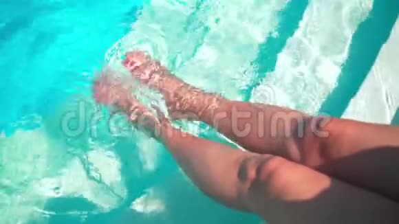 女腿在游泳池里飞溅女孩她的腿在游泳池的清澈的水中闪闪发光视频的预览图