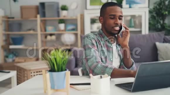年轻的非裔美国人专家在手机上和商务人士交谈笑着用笔记本电脑工作视频的预览图