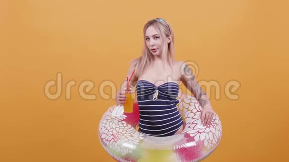 一位身穿泳装的金发女郎喝着鸡尾酒抱着她的游泳圈视频的预览图
