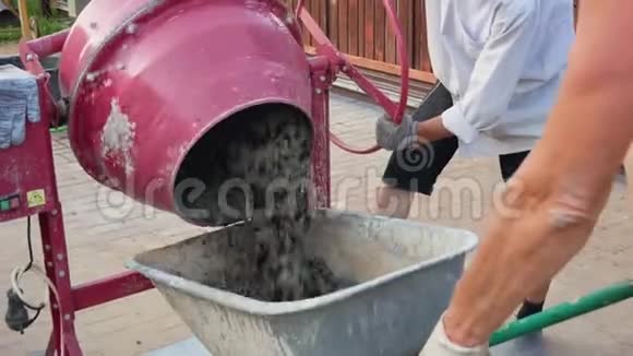 混凝土搅拌机将成品溶液倒入施工现场的手推车中视频的预览图