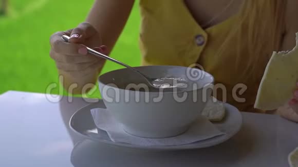 一位年轻女子在一家有着稻田背景的咖啡馆里参与传统东亚美食的特写镜头旅费视频的预览图