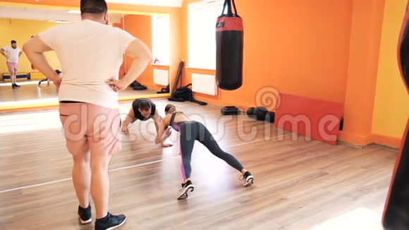 丰满的男人和苗条的女孩健身俱乐部或健身房的个人拳击训练体育锻炼和练习视频的预览图