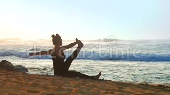 穿着黑色夏季运动服的巨大女孩在海滩上伸展视频的预览图