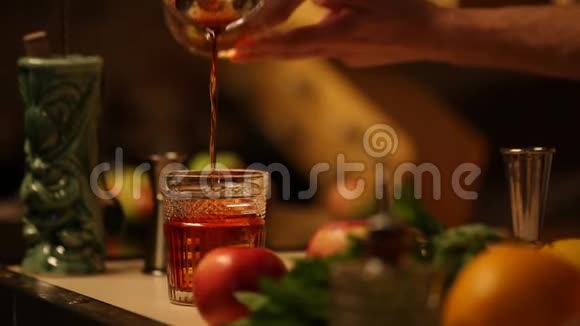 酒保把一杯含酒精的饮料倒进一个装有冰块的玻璃杯里视频的预览图