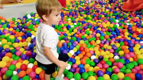 3岁幼儿男孩在泳池操场上玩彩球的4k镜头视频的预览图