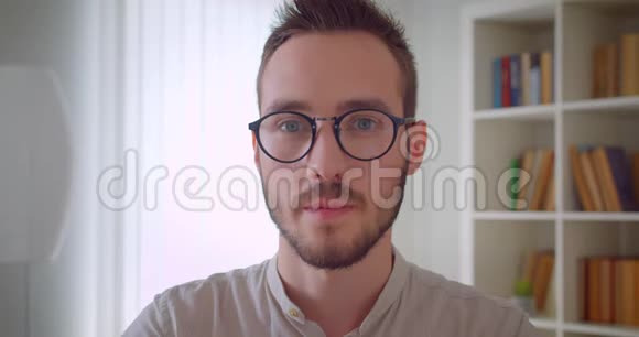年轻英俊的白种人男学生戴着眼镜看着镜头开心地笑着视频的预览图