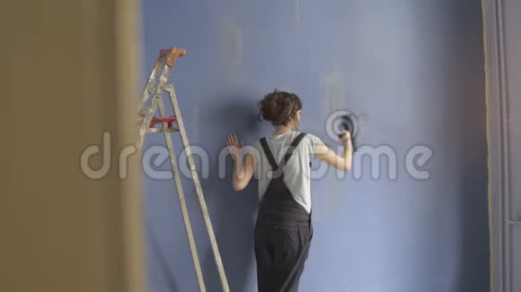 女人装饰新公寓用滚筒粉刷墙壁视频的预览图