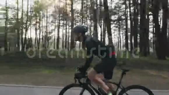 强壮的骑自行车的人在公园里骑自行车阳光透过树木照耀侧跟射击自行车的概念视频的预览图