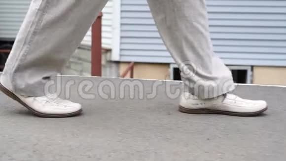 一个人穿着白色的鞋子慢慢地自信地走在城市的小径上视频的预览图