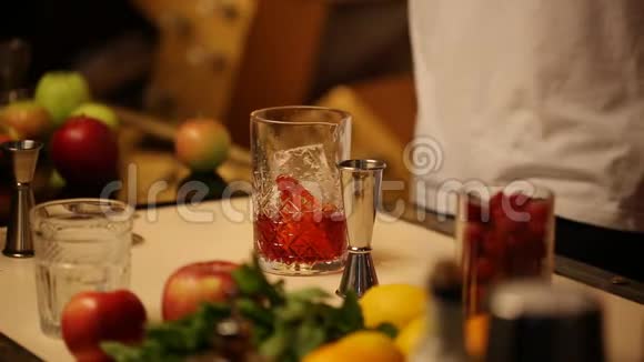 酒吧男用冰块在杯子里搅拌一个薄薄的勺子和一杯鸡尾酒视频的预览图