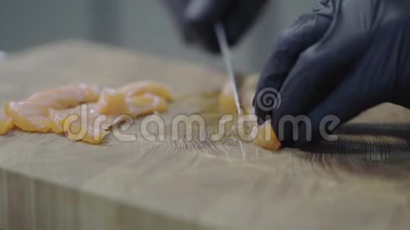 在现代餐厅的特写中用黑色橡胶手套将三文鱼切在木板上海洋食物视频的预览图