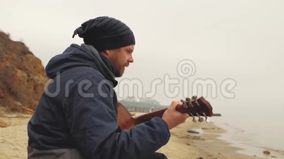 这位戴着针织帽子的人坐在石头上弹吉他从上面弹吉他视频的预览图